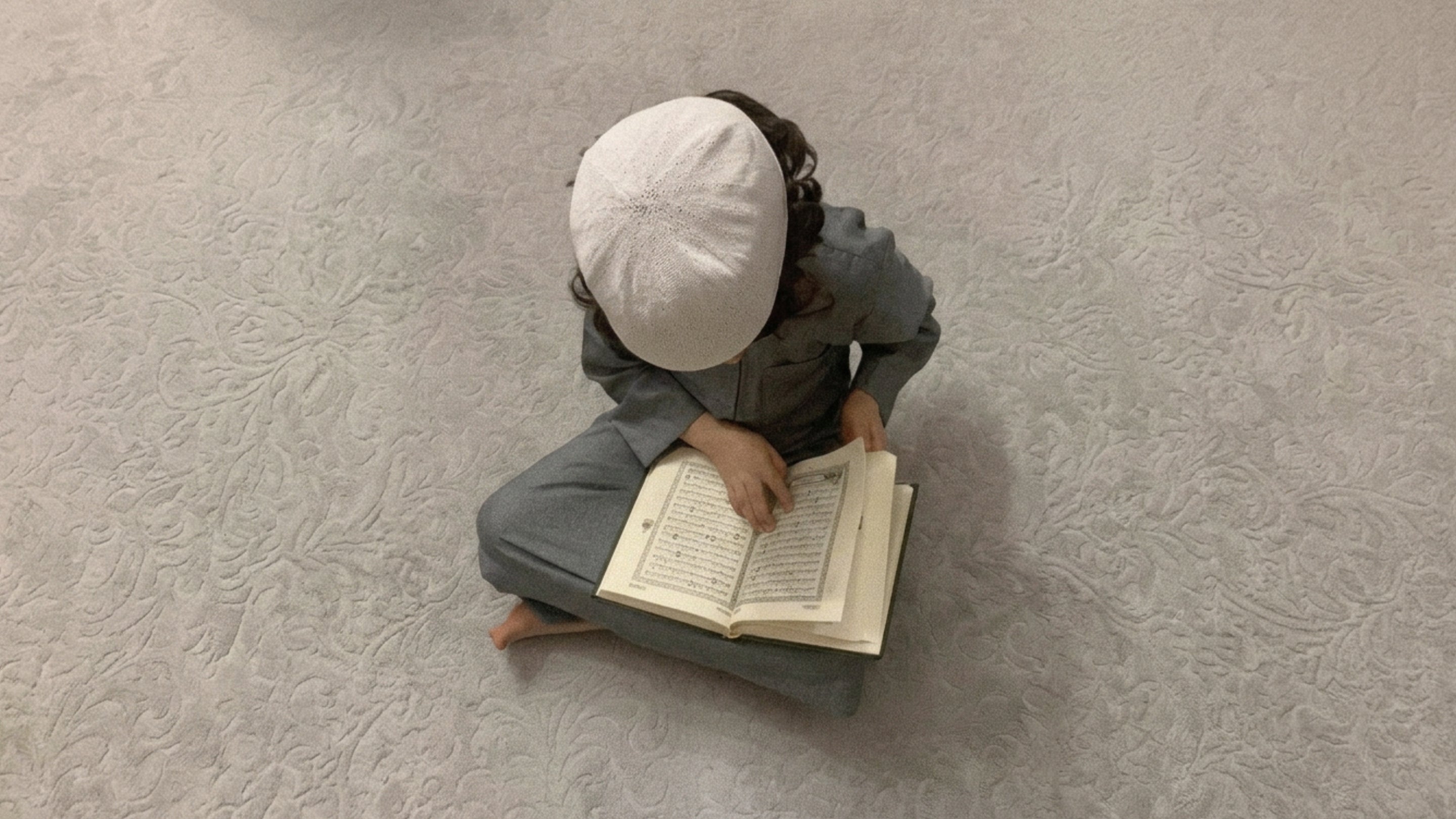 Enfant lisant le Coran sur un tapis